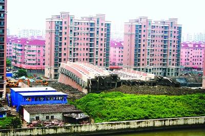 倒塌的樓房位于河邊,底部折斷的水泥柱裸露在外。